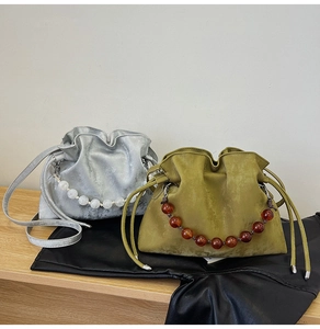 Detailed shot of drawstring bucket bags with beaded handles in silver and moss green colors