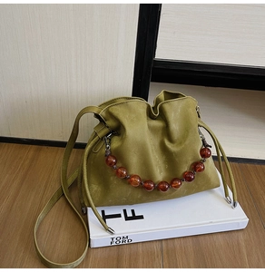 Detail of dark green leather bucket bag with amber beaded handle and drawstring