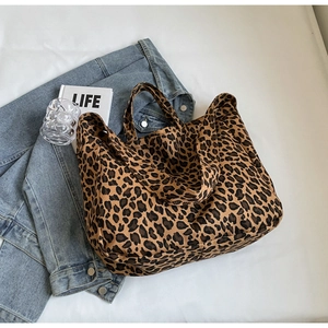 Detail of leopard print canvas tote bag with wide handles next to a denim jacket