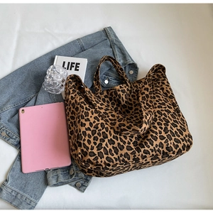 Close-up of leopard print canvas tote bag with sturdy handles on denim jacket