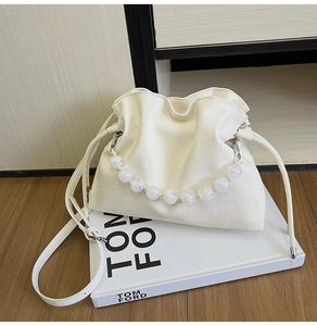 Detail of cream pleated cloud bucket bag with large pearl handle and adjustable strap