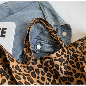 Flat lay of a leopard print canvas tote bag paired with a blue denim jacket background
