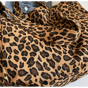Close-up of the leopard print canvas tote bag fabric texture with denim jacket background