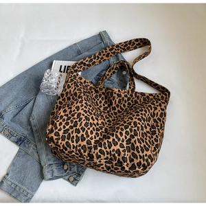Flat lay of a leopard print canvas tote bag with shoulder straps and fashion accessories
