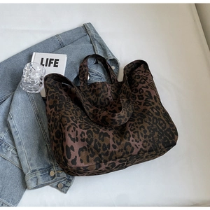 Top-down view of a leopard print canvas tote bag styled with denim and a lifestyle book