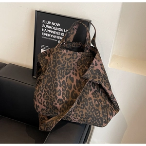Detail view of large leopard print tote bag on leather bench in a modern studio setting