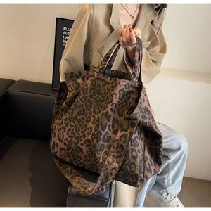 Detail of a large leopard print tote bag with thick fabric texture and dual straps