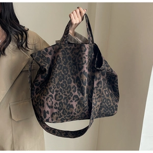 Detailed view of leopard print canvas tote bag carried by model in a stylish trench coat