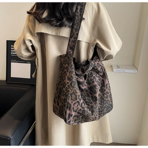 Detailed view of leopard print canvas tote bag carried by a model in a trench coat