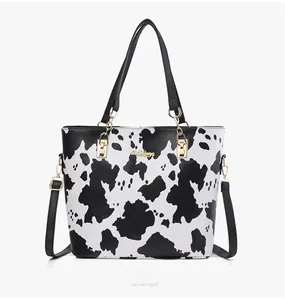 Detailed view of the cow print tote bag with MissBags logo and gold chain accents