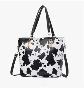 Detail view of cow print tote bag with gold hardware and adjustable strap