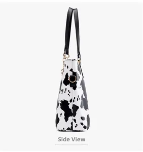 Side view of cow print tote bag with black shoulder strap and gold metal D-ring detail