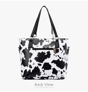 Detail view of the back side of a cow print tote bag with a metal zipper pocket