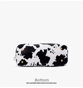 Detailed bottom view of cow print tote bag with four protective gold metal feet studs