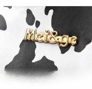 Close-up of golden Mei&ge logo and textured cow print leather on the shoulder bag
