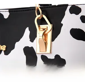 Detailed macro view of reinforced gold metal hardware on cow print tote bag strap