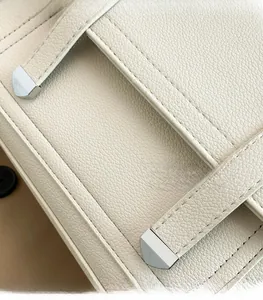 Detailed close-up of cream lychee texture leather with silver metal tip and neat stitching