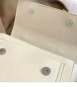 Detail view of premium lychee grain leather handbag with magnetic metal snap fasteners