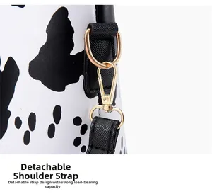 Macro detail of cow print tote bag featuring a detachable shoulder strap with gold metal clasp