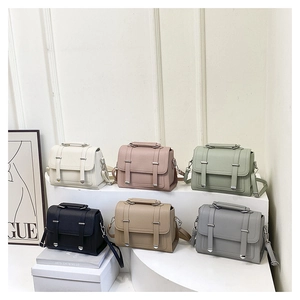 Detail view of stylish litchi grain leather handbags in six trendy colors on a display stand