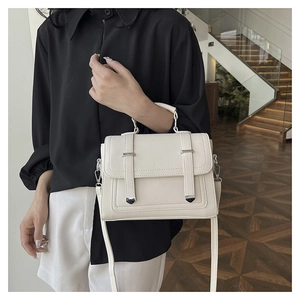 Detailed close-up of cream textured leather shoulder bag with silver metal accents