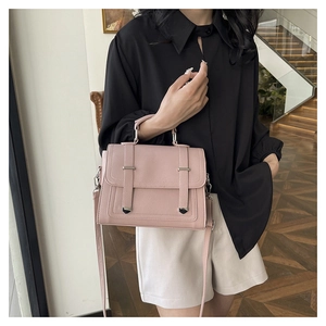 Detail of pink PU leather handbag showing flap cover, silver buckles, and top handle