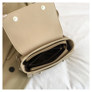 Macro view of beige crossbody bag interior showing multiple compartments and pebbled leather