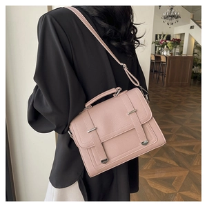 Pale pink lychee grain leather crossbody bag shown on model in a modern cafe setting