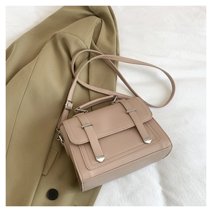 Close-up of litchi texture on light pink handbag with silver buckles and handle details