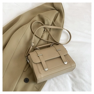 Detail view of khaki faux leather satchel bag with silver hardware and top handle