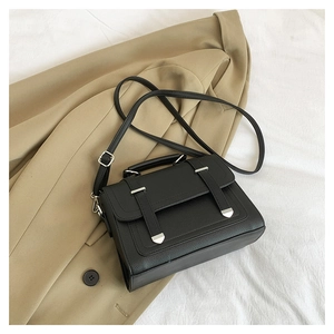 Detail of black pebbled leather handbag with silver metallic buckle straps and top handle