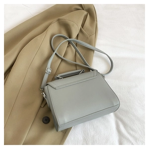 Top view of grey leather handbag with silver hardware on chic blazer and fabric background