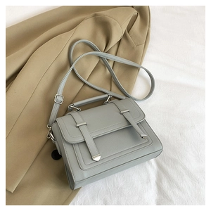 Detail of grey pebbled leather crossbody bag with silver hardware on blazer background