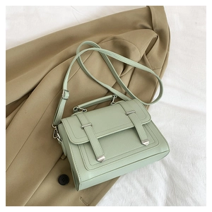 Close-up of mint green vintage shoulder bag on a beige blazer showing grainy texture