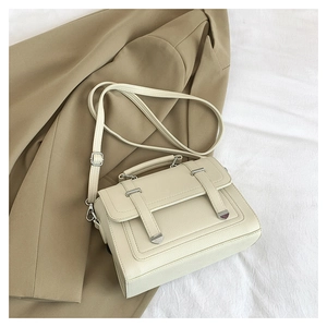Close-up of minimalist cream white leather handbag with silver hardware on camel coat