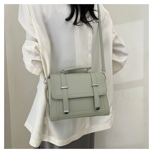 Close-up of mint green leather handbag with silver metallic studs and pebbled texture
