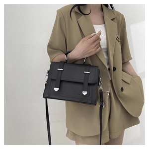 Detailed view of a black retro satchel with lychee grain texture and metal tips