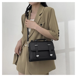 Classic black litchi texture crossbody bag with silver buckles worn by a model