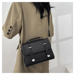 Detail of black lychee grain leather handbag styled with a minimalist brown suit