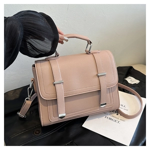 Close-up of litchi-textured pink handbag with silver buckles and flap design details