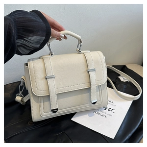 Detail of cream faux leather handbag with lychee texture and silver metal buckles