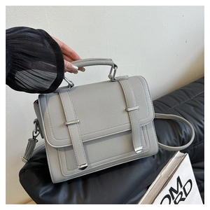 Detail view of light grey handbag with pebble texture and metallic vertical accents
