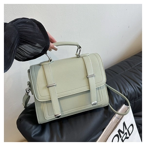 Detail of sage green lychee pattern faux leather handbag with silver buckles and handle