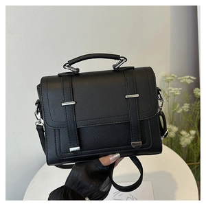 Detail of black lychee grain PU leather handbag with silver metallic hardware and handle