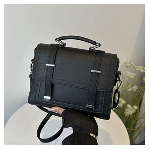 Detailed close-up of a black lychee texture flap bag with silver buckles held by a model