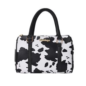 Boston style tote bag featuring black and white cow print with gold metal logo