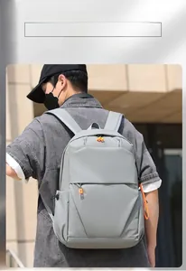 Outdoor shot of minimalist grey backpack featuring vibrant orange zipper pulls for men