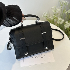 Classic black pebbled leather handbag with silver hardware and top handle on white desk
