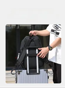 Detail of black backpack with a wide luggage strap secured on a silver suitcase handle