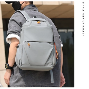 Outdoor view of a minimalist grey waterproof backpack with vibrant orange zipper pulls